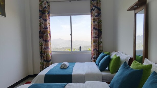 A hotel room with two beds, a large window, and a view of the mountains.