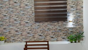 A room with a brick-patterned wall, a wooden chair, and potted plants.