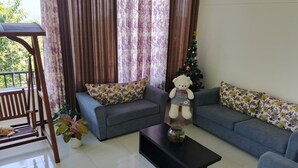 A living room with two sofas, a coffee table, a teddy bear, and a Christmas tree.