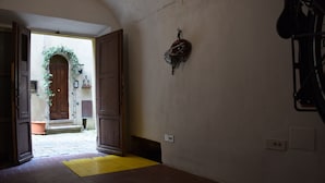 Corredor interno com porta de madeira, tapete amarelo e capacete de bicicleta fixado na parede.