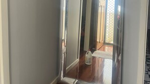 Un pasillo con un espejo grande, un cuadro enmarcado y una puerta que da a otra habitación.