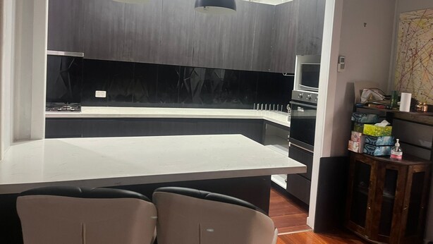 Una cocina moderna con una isla central, luces colgantes y un comedor con sillas.