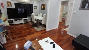 Un salón con televisor, mesa de comedor y sillas.