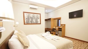 A hotel room with a bed, a wooden wardrobe, a mirror, a flat-screen TV, and a framed artwork on the wall. - Sunkiest House Canggu (Tibubeneng)
