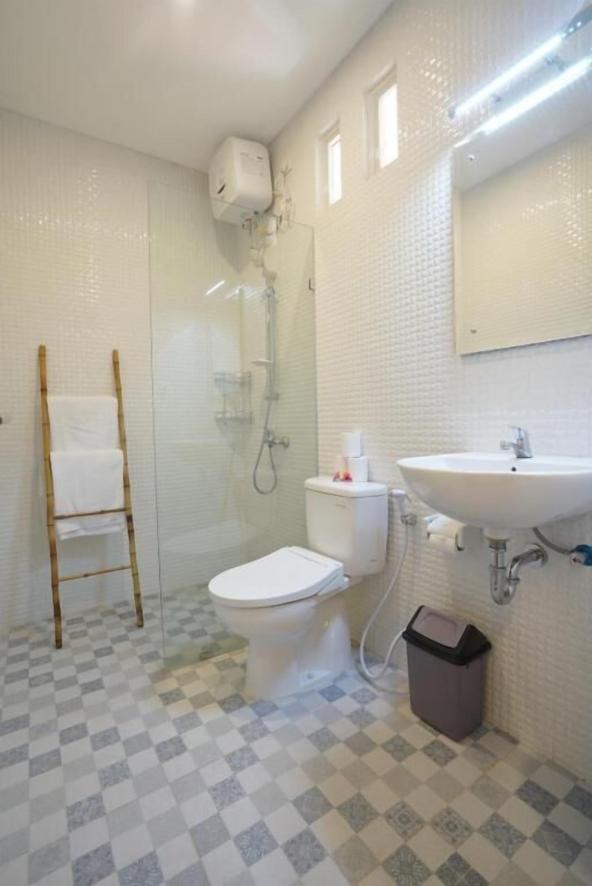 Un baño con inodoro, lavamanos, ducha y toallero.