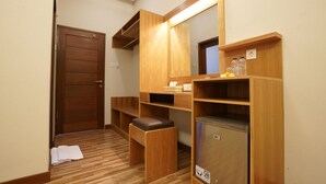 A hotel room with a wooden bench, a small stool, a built-in refrigerator, and a mirror with integrated lighting. - Sunkiest House Canggu (Tibubeneng)
