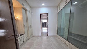 A hallway with a tiled floor, a door on the left, and a glass partition on the right. - Posh Classic, sector 45, millenium city centre, gurugram (Gurugram)