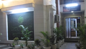 A hotel entrance with a large window, potted plants, and a sign for 'Posh Classic'. - Posh Classic, sector 45, millenium city centre, gurugram (Gurugram)