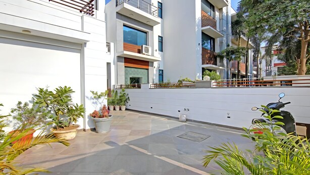 A modern building with a flat roof, large windows, and a paved courtyard with potted plants. - Posh Classic, sector 45, millenium city centre, gurugram (Gurugram)