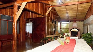 A rustic wooden interior with a fireplace, wooden beams, and a bed with a red blanket.