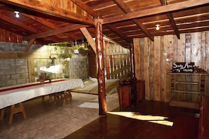 A rustic wooden interior with a long table, stone walls, and hanging plants. - Santa Ana City Views Chalet (Pabellón)