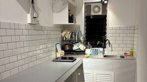 A compact kitchen with white cabinetry, a built-in stove, a sink, and a dish rack. - House for rants very goo (Rawai)