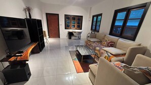 A living room with a TV, sofa, coffee table, and a dining area with a table and chairs. - House for rants very goo (Rawai)