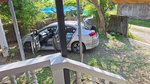 A car parked in a covered outdoor area with a wooden roof and a metal railing. - House for rants very goo (Rawai)