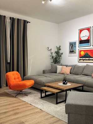 A modern living room with a grey sofa, an orange armchair, a wooden coffee table, and a potted plant. - VibeHaus Center of Split City only 400m from Beach (Split)
