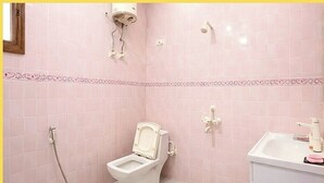 A bathroom with a toilet, shower, and sink.