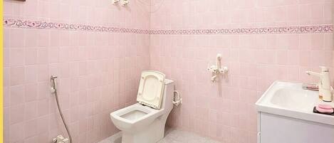 A bathroom with a toilet, shower, and sink.
