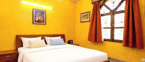 A hotel room with a bed, a nightstand, a window with curtains, and a ceiling with a decorative design.
