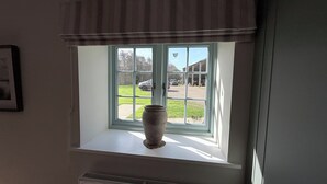 Ein Fenster mit Blick auf eine Auffahrt und geparkte Autos, eine Vase auf dem Sims und eine Lüftungsgitter darunter.