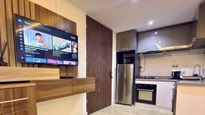 Una cocina moderna con televisor integrado, electrodomésticos de acero inoxidable y armarios de madera.