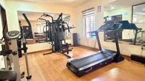 Un gimnasio con cintas de correr, máquinas de pesas y un espejo grande.
