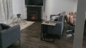 Ein Wohnzimmer mit Kamin, Flachbildfernseher und zwei Sofas.