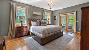 Quarto com uma cama grande, cómoda de madeira e um candelabro.