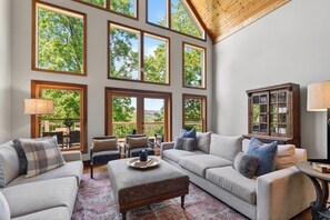 A spacious living room with multiple large windows, a wooden ceiling, and a cozy seating area with a fireplace. - HotTub + Arcade Games + Yoga Room + Expansive Deck + Views | Rocking Chair Ridge (Sevierville)