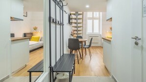Ein modernes, kompakes Wohnzimmer mit Essbereich, Küchenzeile und einer Treppe.