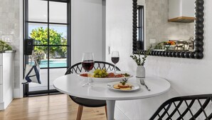A dining area with a round table, chairs, a glass of red wine, a bowl of grapes, and a plate of food. - Private Pool + Firepit + Ping Pong + Expansive Backyard | Mins to Dining (Scottsdale)