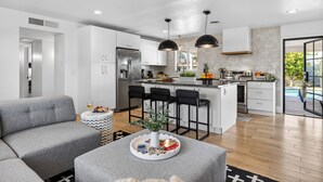 A modern kitchen with white cabinets, a central island, and black bar stools. - Private Pool + Firepit + Ping Pong + Expansive Backyard | Mins to Dining (Scottsdale)