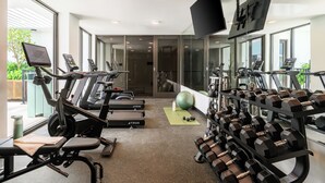Un gimnasio con cintas de correr, mancuernas y pelotas de ejercicio.
