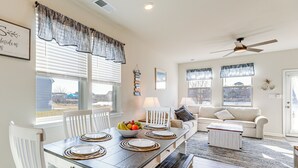 A dining area with a table set for four, a sofa, a ceiling fan, and a view of the outside. - 4 Mi to Boardwalk! Bethany Beach Getaway (Millville)