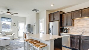 A modern kitchen with dark wood cabinets, a stainless steel refrigerator, and a large island with bar stools. - 4 Mi to Boardwalk! Bethany Beach Getaway (Millville)