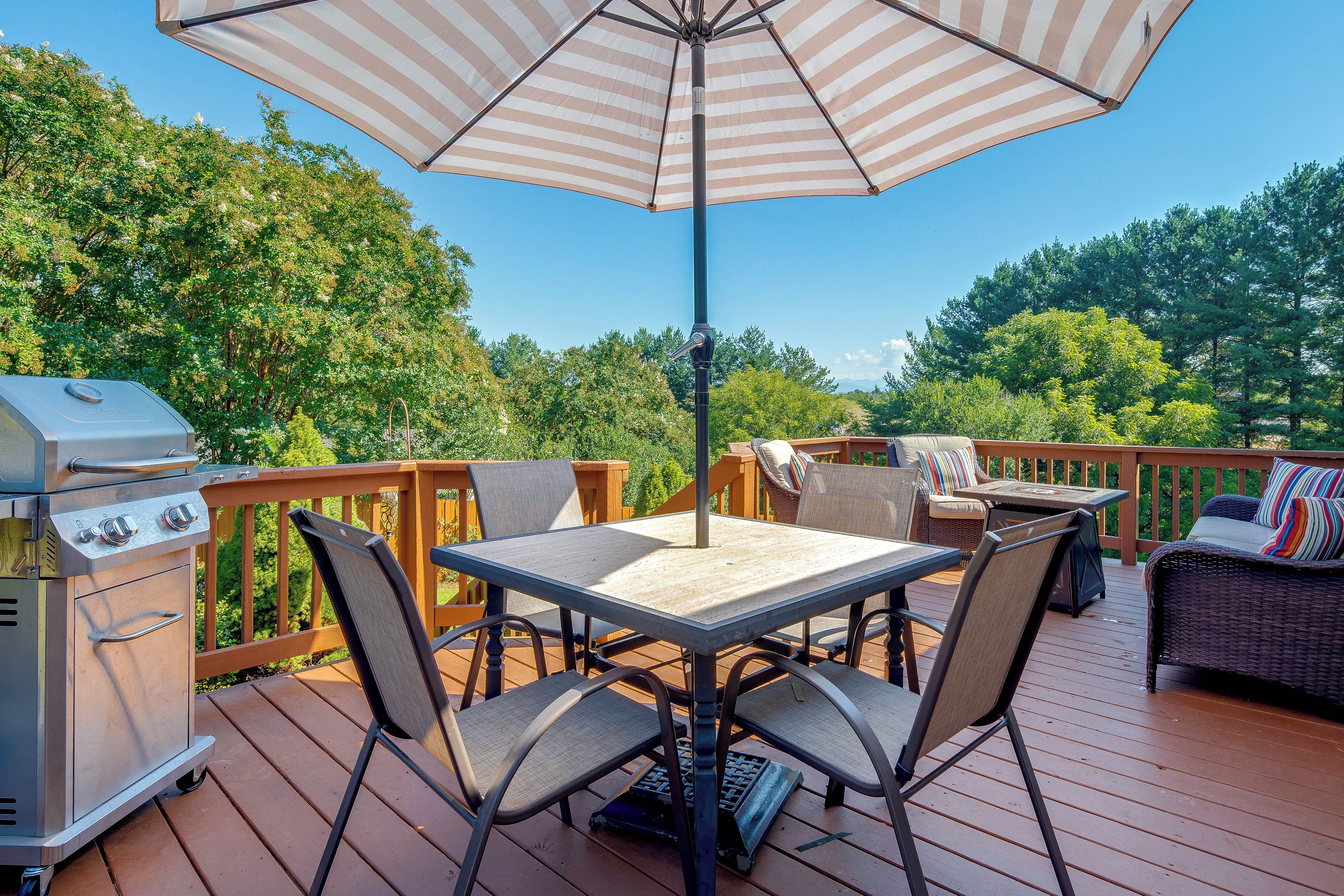Une terrasse extérieure avec une table, des chaises, un barbecue et un parasol.