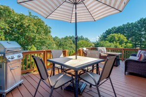 An outdoor deck with a table, chairs, a grill, and an umbrella.