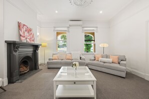 Una sala de estar con chimenea, dos sofás, una mesa de centro y un ventanal con vistas.