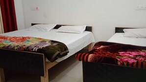 Dos camas individuales con ropa de cama blanca, una manta floral en la cama de la izquierda y una manta rojo oscuro en la cama de la derecha.