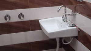 Un baño con un lavamanos blanco, un espejo y paredes con baldosas a rayas.