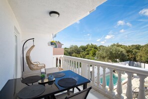 A balcony with a table, chairs, a hanging chair, and a view of a swimming pool and greenery. - Croatia/Istria🇭🇷🌊🏖️☀️ villa-liznjan a villa 2 apartments (Ližnjan)