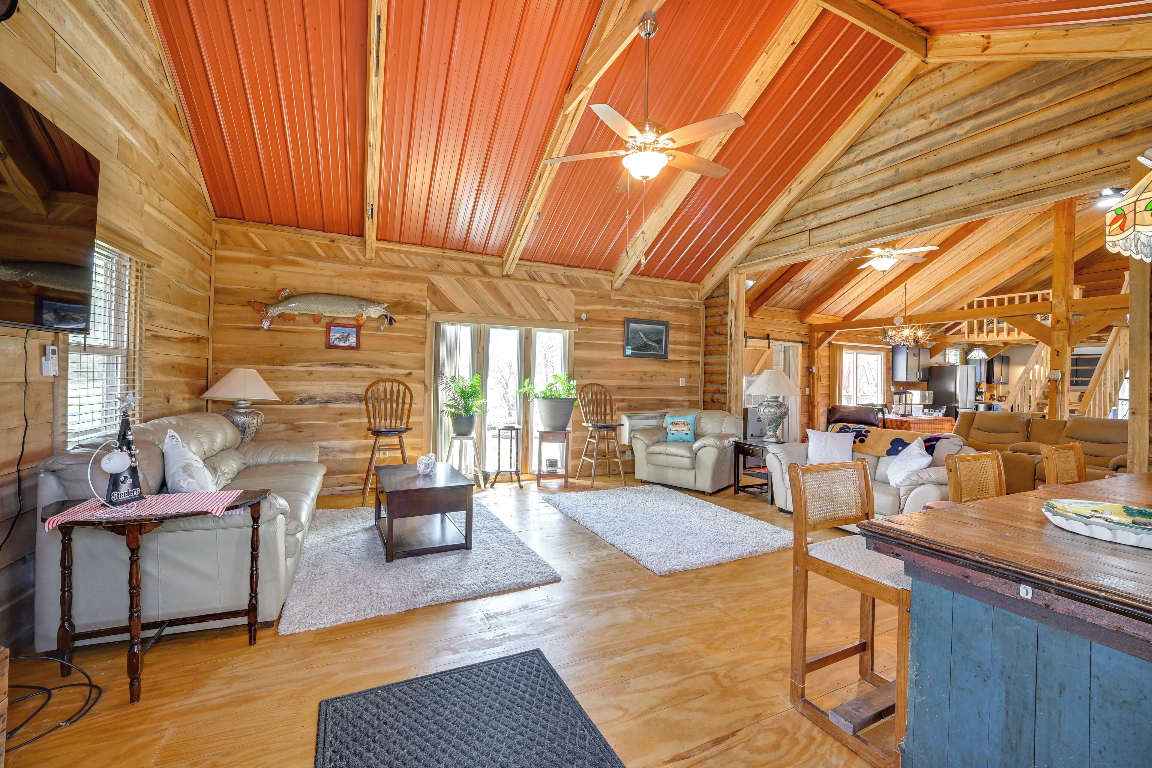 Een ruim houten blokhutinterieur met een eethoek, keuken en zithoek.