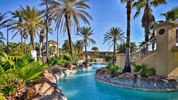 A pool area with clear blue water, surrounded by rocks and palm trees. - Disney Magic & Resort Fun! Family Gem in Davenport (Davenport)
