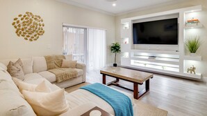 A living room with a sofa, a coffee table, a TV, and a decorative wall piece. - Disney Magic & Resort Fun! Family Gem in Davenport (Davenport)