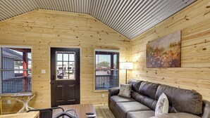 Un accogliente interno di una baita con arredamento in legno, un divano, un tavolo e un quadro appeso al muro.