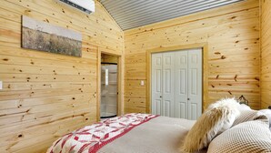 Una stanza in legno con un letto, una porta e un condizionatore d'aria a parete.