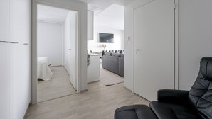 Un espace de vie moderne et minimaliste, comprenant un canapé, un fauteuil en cuir noir et une petite table.