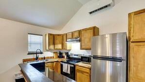 A kitchen with wooden cabinets, stainless steel appliances, and a window with blinds. - 3 Mi to Sabine River: East Texas Cabin Hideaway (Joaquin)