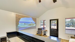 A modern living room with a large window, a black door, and a seating area. - 3 Mi to Sabine River: East Texas Cabin Hideaway (Joaquin)