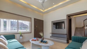 Un salon moderne avec des canapés de couleur turquoise, une table basse en marbre et un téléviseur fixé au mur.