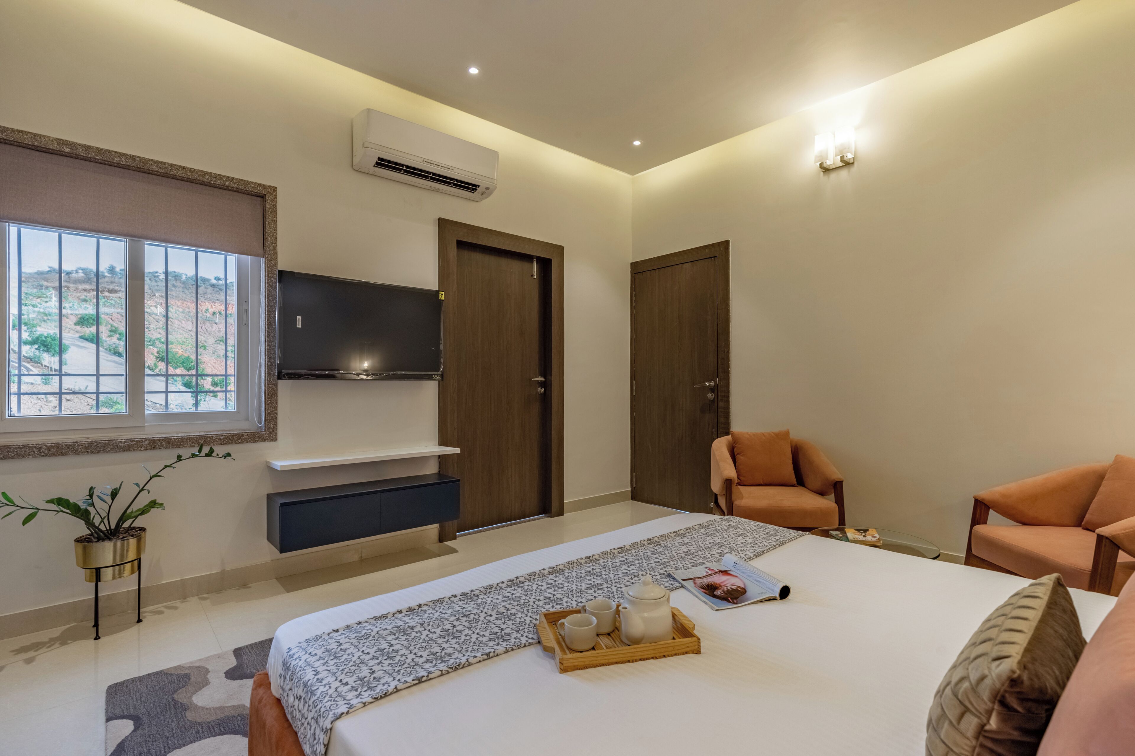 A bedroom with a bed, a TV, a sofa, and a window with a view.